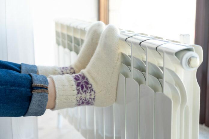 Woman warming up with feet on heater wearing woolen socks