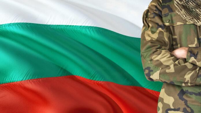 Crossed arms Bulgarian soldier with national waving flag on background Bulgaria Military theme