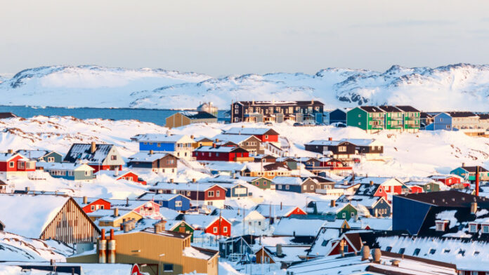 Lots of Inuit houses scattered on the hill in Nuuk city covered in snow with sea and mountains in the background, Greenland